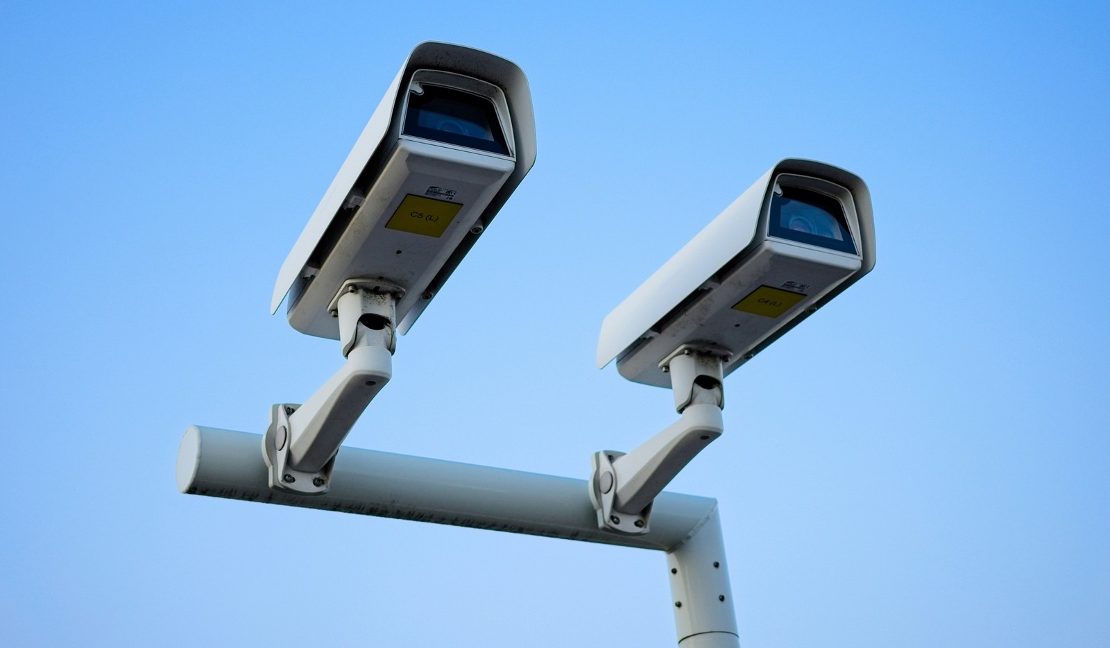 맑은 하늘 아래 기둥 위에 설치된 두 대의 흰색 CCTV 카메라