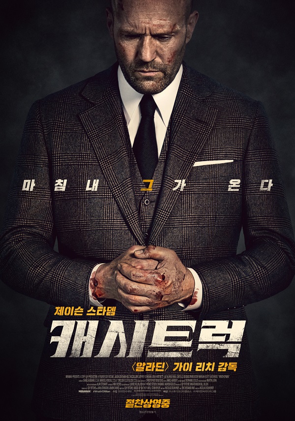 피로한 표정의 남성이 짙은 색 수트를 입고 두 손을 모은 채 서 있고, 손에는 피가 묻어 있으며, 하단에는 거친 타이포로 ‘캐시트럭’ 제목이 적힌 영화 포스터