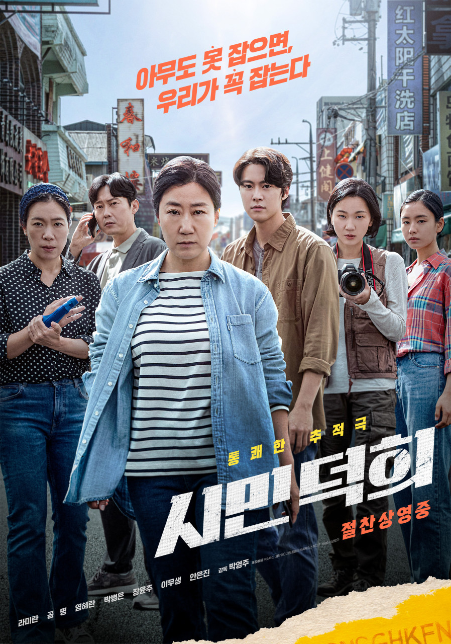 도심 거리 한가운데에서 단정한 단발머리의 중년 여성이 앞장서 걷고 있고, 그 뒤로 휴대폰과 카메라를 든 동료들이 함께 서 있으며, 위쪽에는 “아무도 못 잡으면, 우리가 꼭 잡는다”라는 문구와 ‘시민덕희’라는 제목이 적힌 영화 포스터
